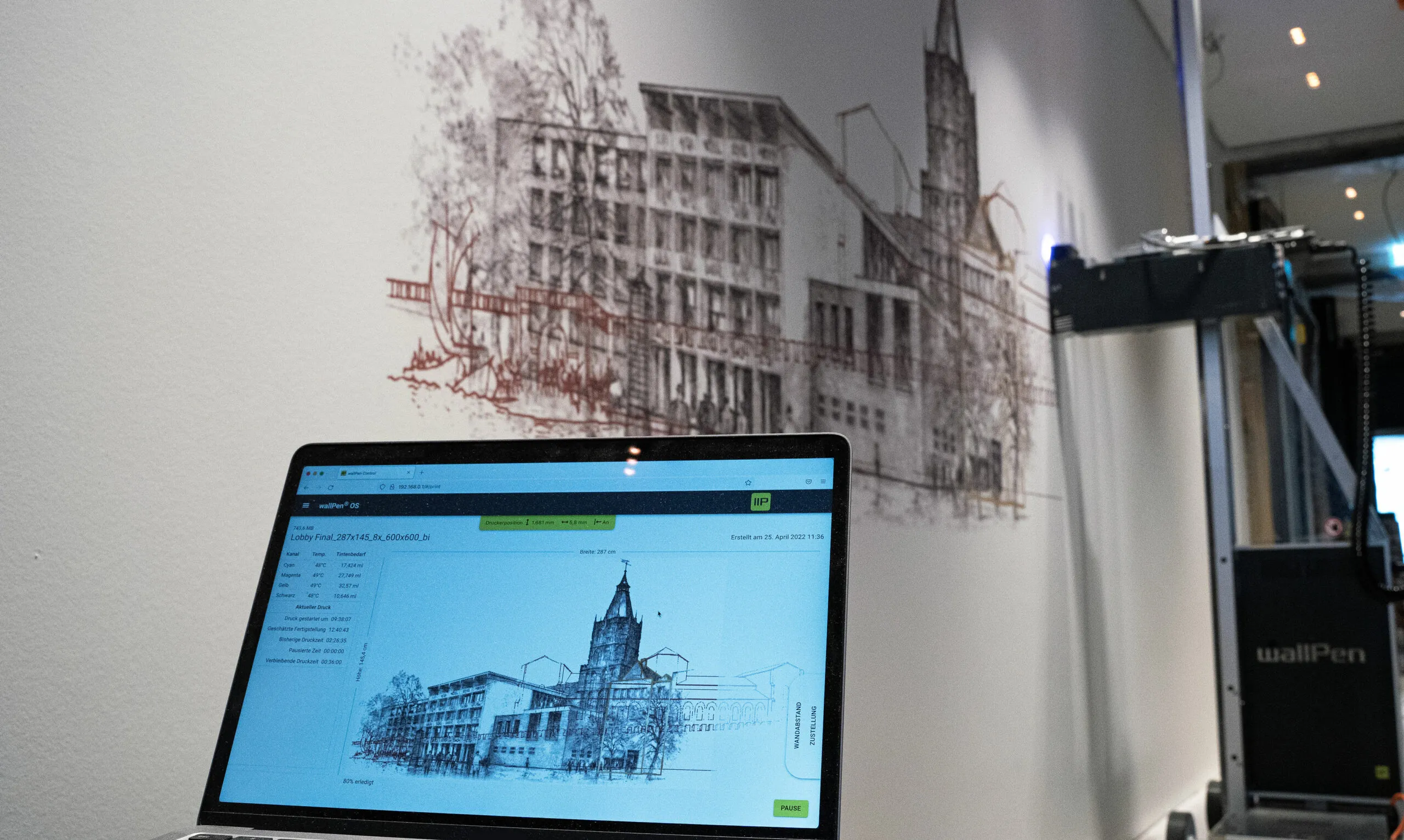 Logiciel de pilotage de l’impression murale affichant les niveaux d’encre et l’avancement, devant un mur en cours d’impression